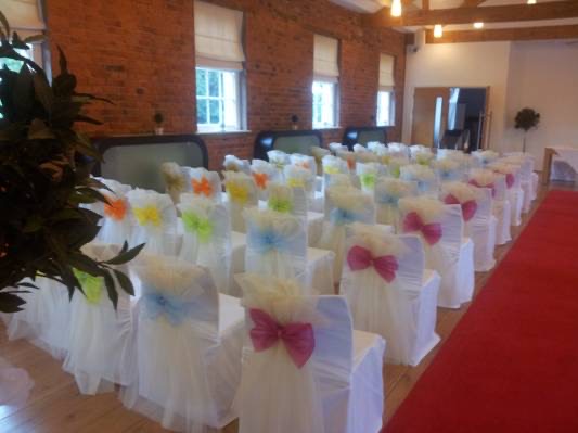 White chair covers with colourful pastel organza bows